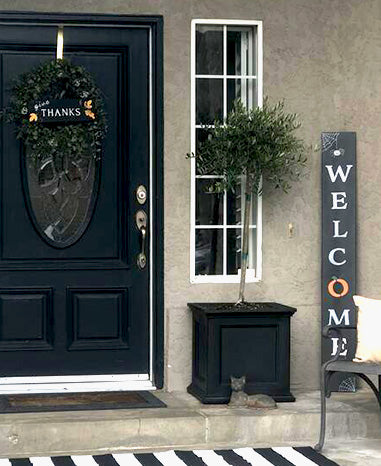 User-generated fall Welcome sign with a pumpkin as the 'O', crafted on a Plata Outdoor Chalkboard using magnetic chalkboard stencils, displayed next to a black door with a 'Thanks' wreath chalkboard sign