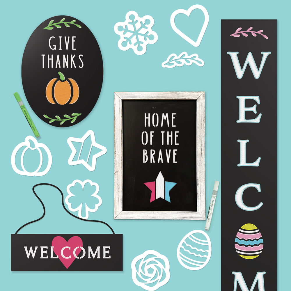 Collection of chalkboards including large outdoor chalkboard, oval frameless chalkboard, framed chalkboard and hanging chalkboard each creatively decorated with magnetic Holiday Chalkboard Stencil Set, featuring themes like &#39;GIVE THANKS,&#39; &#39;HOME OF THE BRAVE,&#39; ‘WELCOME’ and seasonal designs.