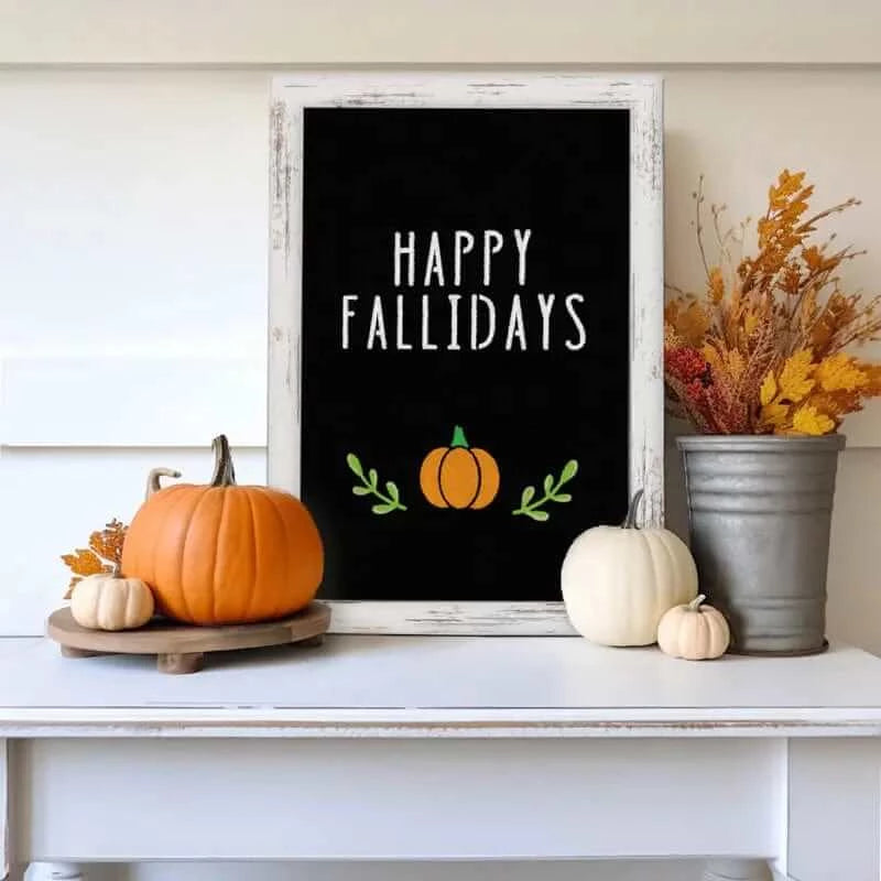 ‘Happy Fallidays’ fall chalk art on white wood framed chalkboard on white mantle surrounded by pumpkins and fall decor, an easy fall craft created using magnetic chalkboard lettering stencils and pumpkin stencils to create a fall chalkboard sign