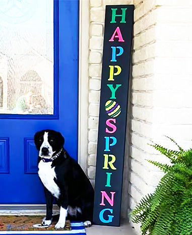 outdoor chalkboard porch sign stenciled 'HAPPY SPRING' in colorful letters with beside a blue door, with a black and white dog sitting next to it