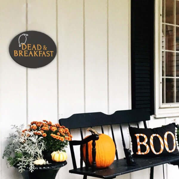 Dead and Breakfast Halloween Sign crafted with Plata Halloween Stencils on a Plata Oval Chalkboard hung horizontally next to front door of a home decorated for Halloween.