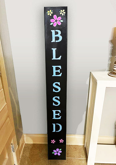 Big chalkboard sign crafted with magnetic letter stencils and chalk markers to display 'Blessed' in white lettering with pink and yellow flowers at top and bottom of sign created with floral stencils to create a spring chalkboard sign 