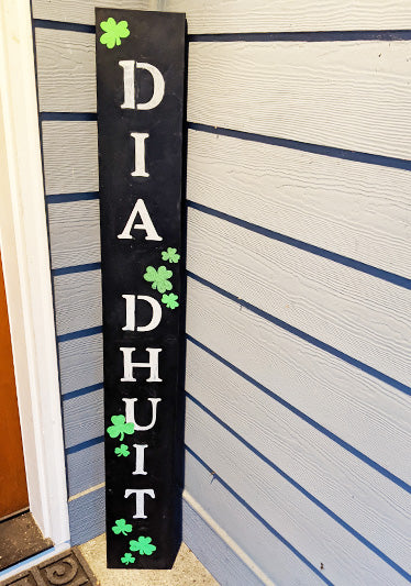 Crafted with magnetic chalkboard stencils, this black weatherproof chalk board features the Irish greeting 'DIA DHUIT' stenciled in bold white letters, accented with shamrocks for a DIY  St. Patrick's Day decoration