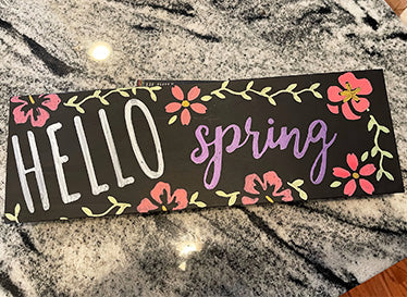 'Hello Spring' hanging chalkboard sign stenciled with a white 'hello' and 'purple' spring spring  surrounded by pink flowers using spring chalkboard stencils