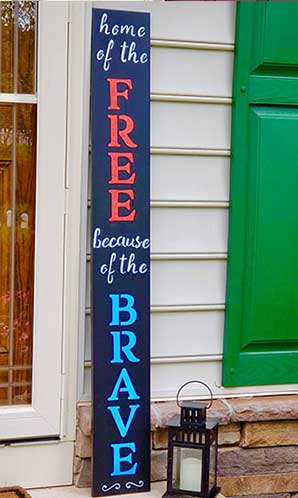 Outdoor blackboard sign next to a green door with 'home of the FREE because of the BRAVE' in blue and red lettering, made using magnetic chalkboard stencils and paint markers, creating a poignant 4th of July decoration that honors bravery and freedom