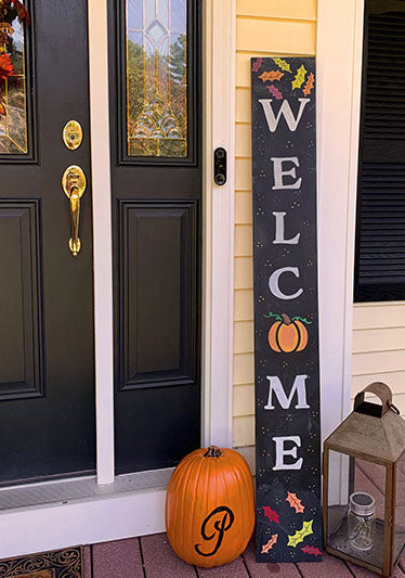 Homemade fall welcome sign created with welcome stencils on a large chalkboard with a pumpkin used as an O in welcome