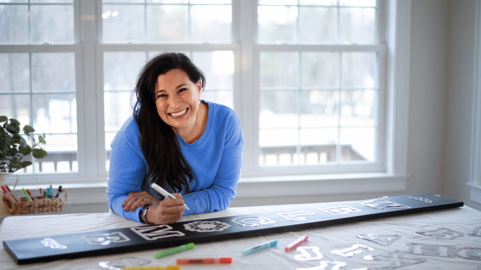 Woman making a DIY welcome sign with letter stencils, painting pens and 5 ft tall vertical porch chalkboard