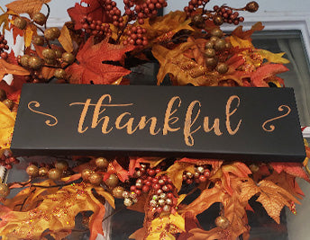"Thankful" Hanging Welcome Sign on a fall wreath made with thankful word stencil and orange painting pen