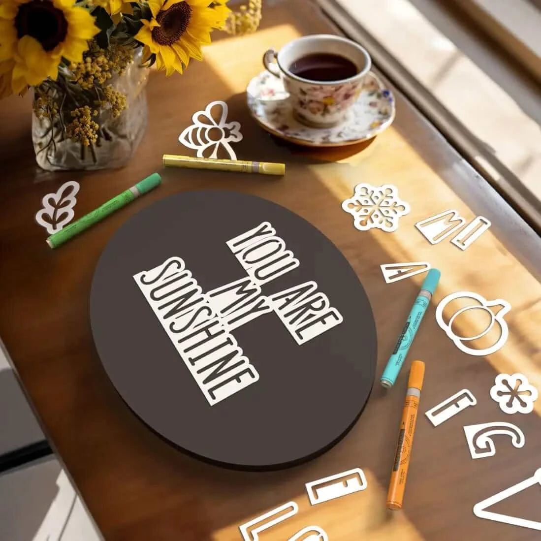 A display of everything included with Plata oval chalkboard sign craft kit- 11" x 14" oval chalkboard, alphabet of magnetic letter stencils, seasonal design stencils (bee, ice cream cone, pumpkin, snowflake stencils), 6 chalk markers and chalkboard eraser for easy DIY signs