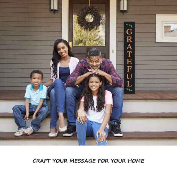 Family sitting on front porch of home in front of tall home sign they crafted together