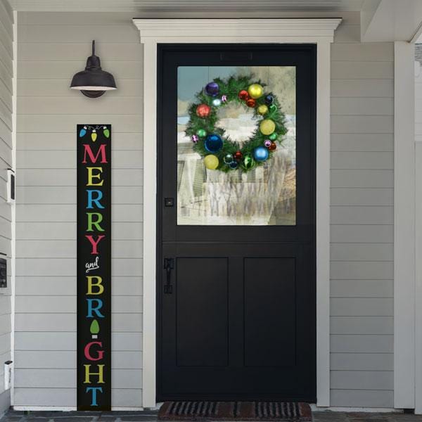 A Plata Porch Chalkboard 5 ft Christmas Sign stenciled to say Merry and Bright in the front of a home decorated for the holidays